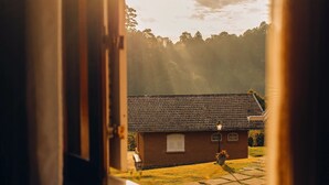 A rustic wooden house with a tiled roof, a small porch, and a single window.