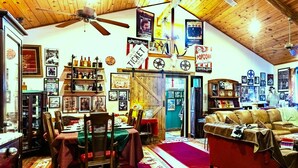 A cozy, rustic interior with a dining area, a living room with a leather sofa, and a ceiling fan. - Here ye, Here ye! Royal Retreat 5 Minutes to Scarborough Renaissance Festival! (Waxahachie)