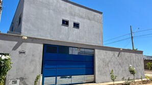 Un edificio moderno con un amplio portón de garaje azul, un ventanal pequeño y un letrero que dice "Casa 01".