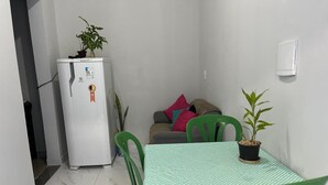 Una habitación compacta con una mesa de comedor, sillas, un refrigerador y una planta en maceta.