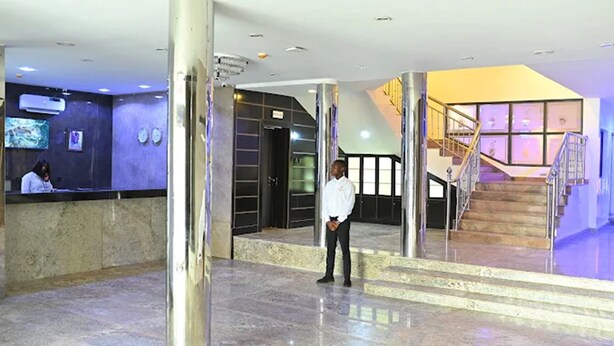 Eine Lobby mit Empfangstresen, einer Treppe und einer Person in der Nähe des Eingangs.