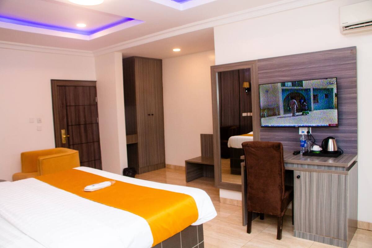 Une chambre d’hôtel équipée d’un lit, d’un bureau, d’une chaise, d’une télévision et d’une armoire.