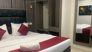 Ein Hotelzimmer mit einem großen Bett, einem Schrank, einem Spiegel und einem kleinen Tisch.