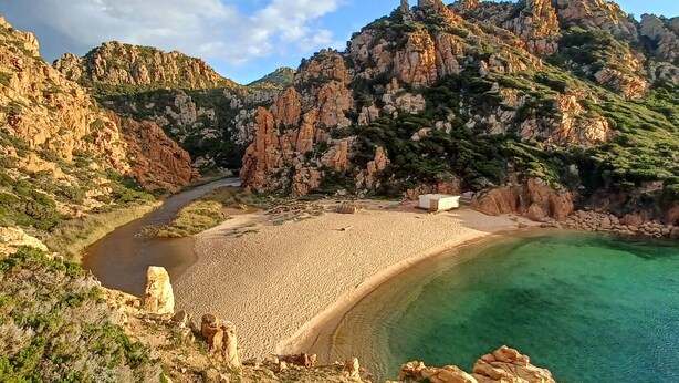 A coastal landscape with a sandy beach, a clear blue sea, and rocky cliffs. - Lovely apartment in Costa Paradiso with swimming pool (Costa Paradiso)