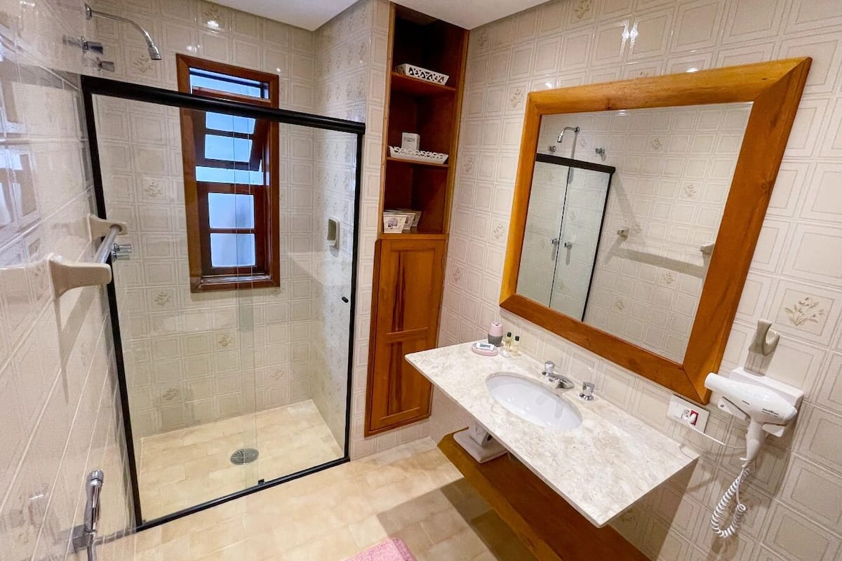 A bathroom with a glass-enclosed shower, a vanity with a sink, and a large mirror.