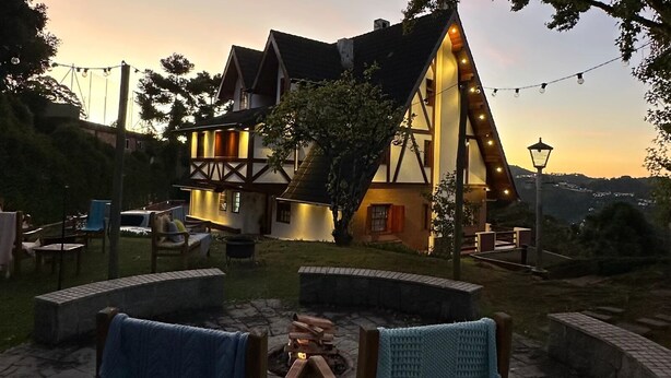 A traditional half-timbered house with a stone fire pit and outdoor seating. - Hortelã Village (Campos do Jordão)