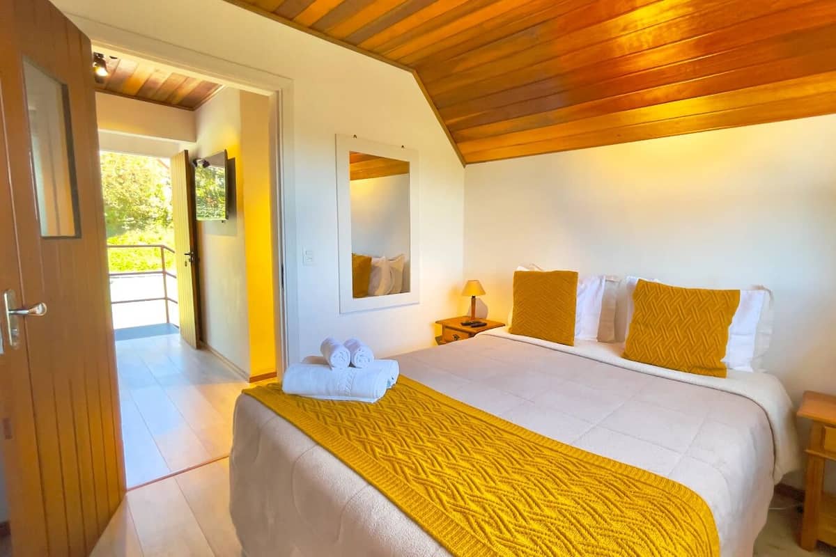 A hotel room with a bed, a nightstand, a mirror, and a door leading to a balcony.