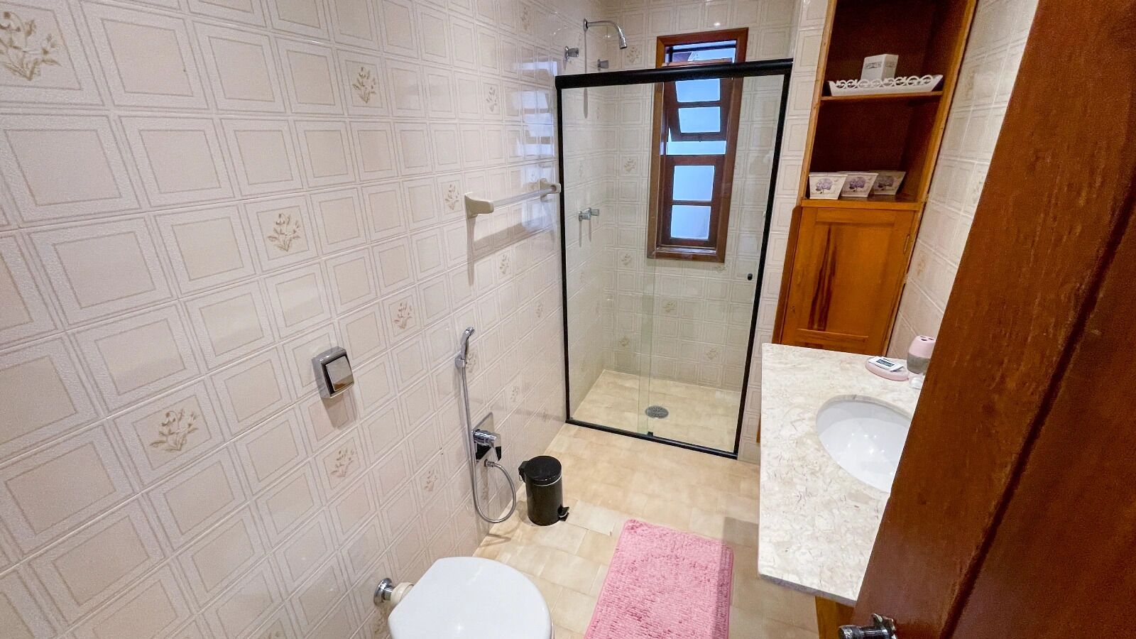 A bathroom with a toilet, shower, and a glass-enclosed shower stall.