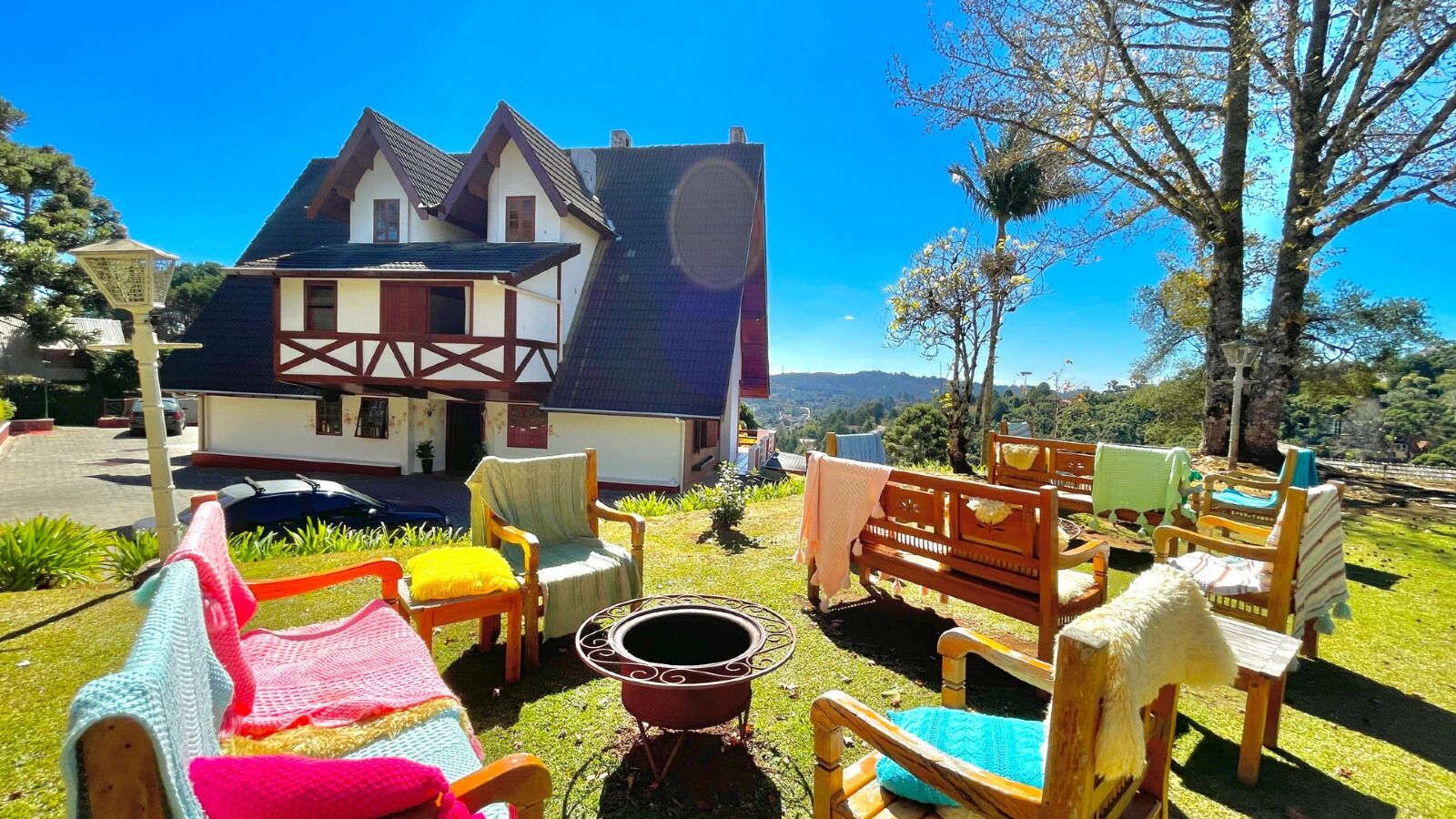 Une maison traditionnelle dotée d’un balcon, d’un espace extérieur aménagé avec des chaises et une table, et offrant une vue sur le paysage environnant.