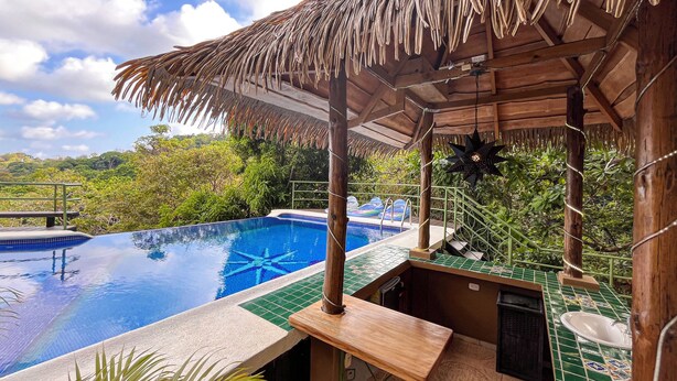 A pool area with a thatched roof, a wooden bench, and a view of the surrounding greenery. - Villa Grande – Spacious 5-Bedroom Retreat with Private Pool in Manuel Antonio (Quepos)