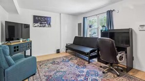Una sala de estar moderna con un sofá, una silla, un televisor y un escritorio.