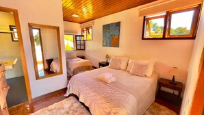 A bedroom with a large bed, a mirror, two bedside tables, and a window. - Pousada Hortelã (Campos do Jordão)