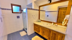 A bathroom with a shower, a sink, and a mirror. - Pousada Hortelã (Campos do Jordão)
