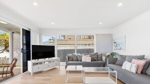 Un salon moderne avec un canapé, un téléviseur et une table basse.