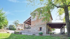 A stone building with a wooden roof, a covered patio, and a stone staircase leading to a door.