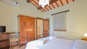 A bedroom with a bed, a desk with a chair, a wardrobe, and a television.