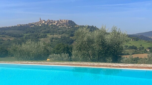 A swimming pool with a view of a hillside town.