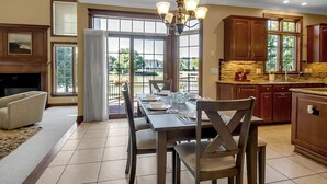 Una cocina amplia con armarios de madera, un comedor con candelabro y vistas a través de grandes ventanales.