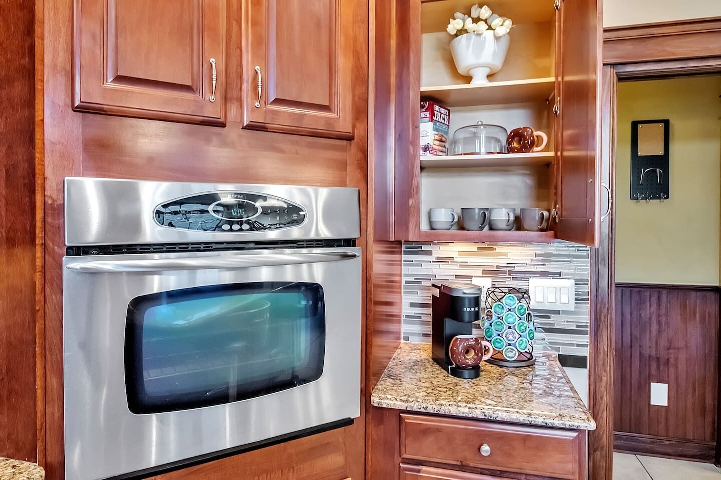 A kitchen with stainless steel appliances, wooden cabinets, and a countertop with a coffee maker and decorative items.