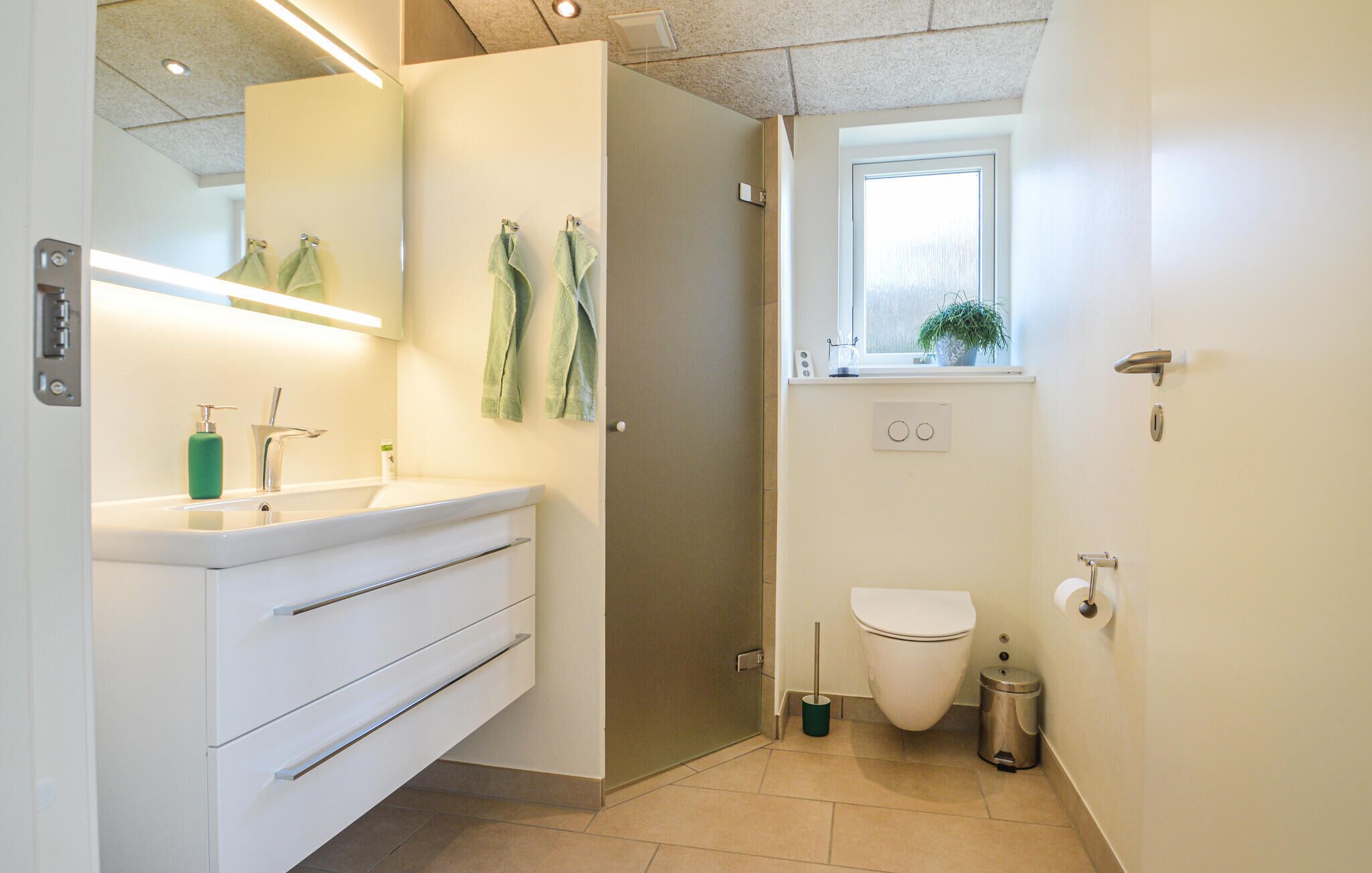 A modern bathroom with a white vanity, a shower, and a toilet.