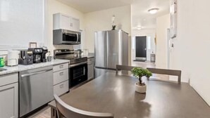Una cocina moderna con electrodomésticos de acero inoxidable, microondas empotrado y cafetera sobre la encimera.