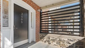 Entrada de un edificio con una puerta marcada con el número 2505, fachada de ladrillo y una reja metálica.