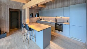 A modern kitchen with a central island, bar stools, a built-in oven, and a coffee station. - Lovely home in Gålå with sauna (Gålå)