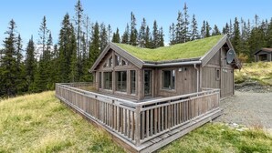 A wooden cabin with a green roof, a deck, and a view of a forested area. - Lovely home in Gålå with sauna (Gålå)