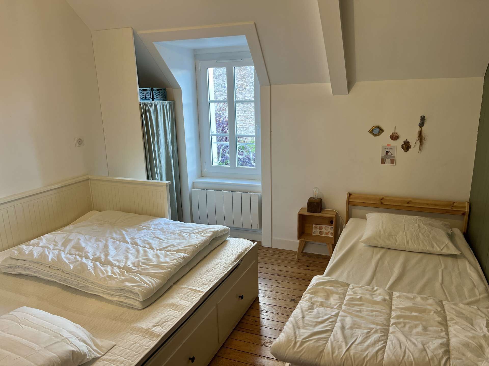 A bedroom with two beds, a window, and a radiator.