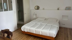 A bedroom with a wooden bed, a white door, a mirror, and a small shelf with a candle and picture.