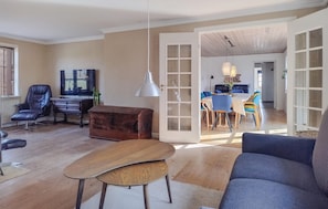 A living room with a sofa, a wooden coffee table, a leather chair, a television, and a dining area with a table and chairs. - Pet friendly home in Sønder Felding with WiFi (Sønder Felding)