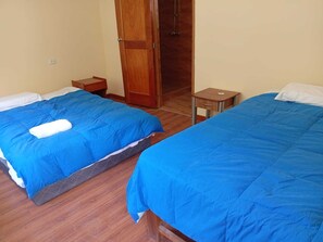 Two beds with blue bedding, a wooden wardrobe, and a small wooden nightstand. - Glamping Machupicchu Lodge (Santa Teresa)