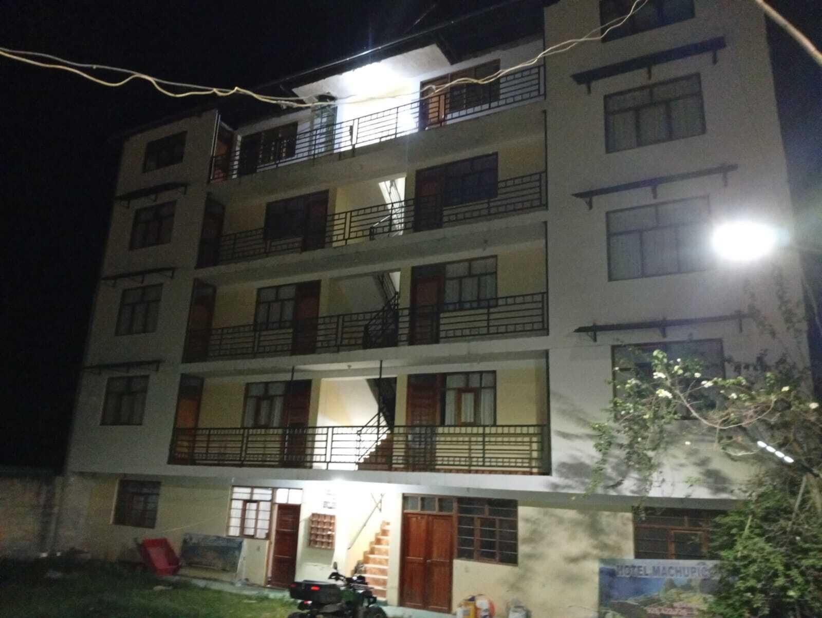 A multi-story building with balconies, a staircase, and a sign indicating a hotel.