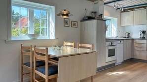 Ett modernt kök med träskåp, en inbyggd ugn och en matplats med bord och stolar.