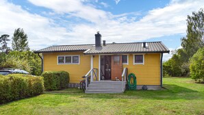 A yellow house with a tiled roof, a front porch, and a green hose on the side. - 3 bedroom awesome home in Sölvesborg (Sölvesborg)