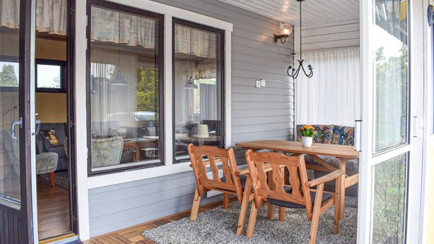 A cozy room with a wooden table and chairs, large windows with curtains, and a hanging light fixture. - 3 bedroom awesome home in Sölvesborg (Sölvesborg)