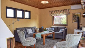 A cozy living room with a sofa, two armchairs, a coffee table, and a rug. There are two windows with curtains, a ceiling fan, and a painting on the wall. - 3 bedroom awesome home in Sölvesborg (Sölvesborg)