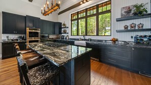 Una cocina moderna con armarios oscuros, una isla grande y un ventanal con vistas al exterior.