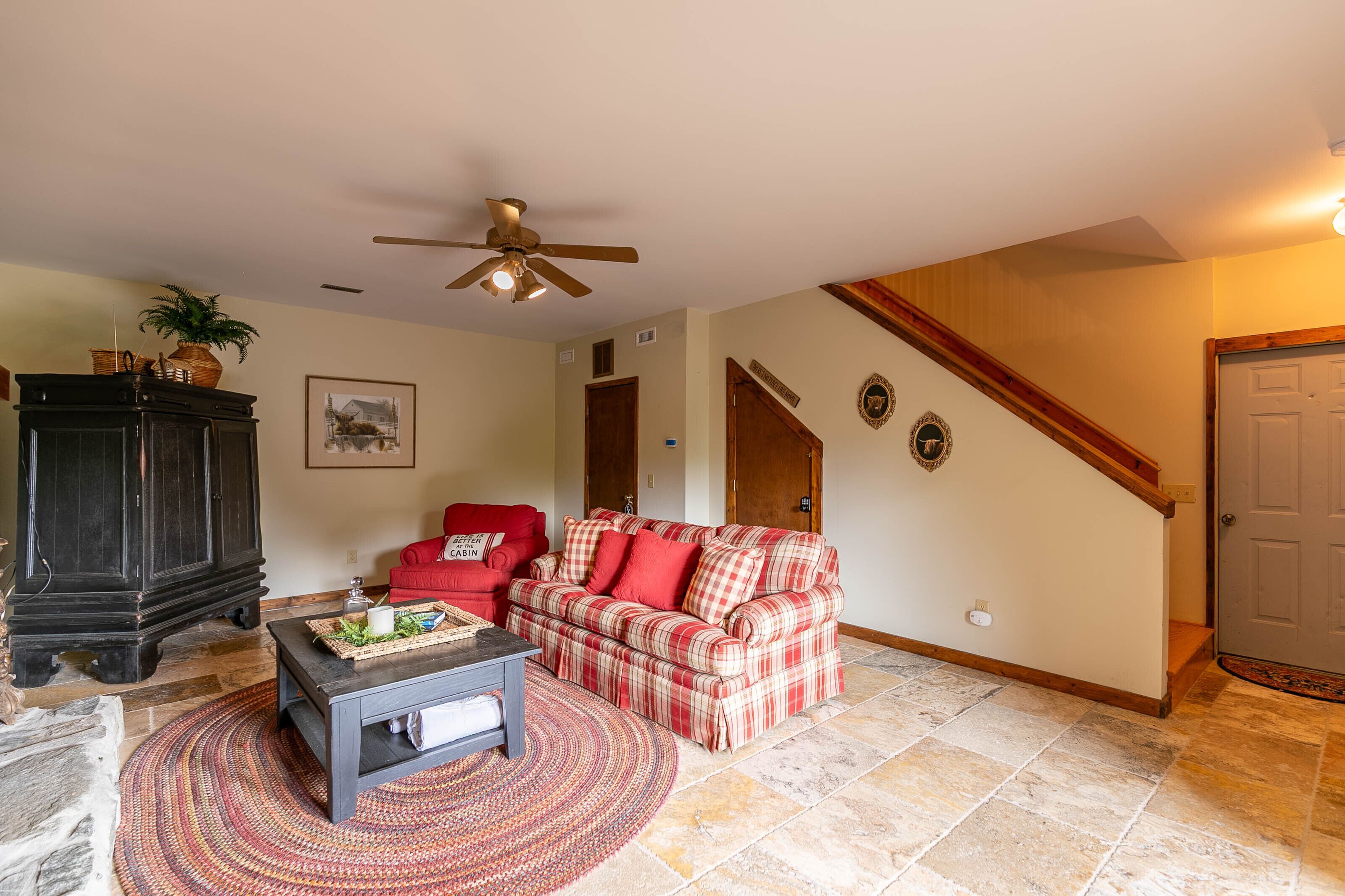 A living room with a red sofa, a dark wooden cabinet, and a ceiling fan.