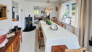 A long dining table with a white tablecloth, surrounded by wooden chairs. A chandelier hangs from the ceiling, and there is a window with curtains on the right side. - 3 bedroom stunning home in Grebbestad (Grebbestad)