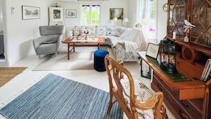 A cozy living room with a grey armchair, a patterned sofa, a wooden coffee table, and a blue ottoman. - 3 bedroom stunning home in Grebbestad (Grebbestad)