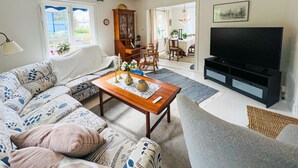 A living room with a sofa, coffee table, TV, and a dining area with chairs and a table. - 3 bedroom stunning home in Grebbestad (Grebbestad)