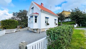 A white building with a red roof, a small porch, and a gravel driveway. - 3 bedroom stunning home in Grebbestad (Grebbestad)