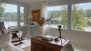A cozy room with a lake view, featuring a rocking chair, a wooden coffee table, and a tripod-mounted camera. - Beautiful home in Säffle with lake view (Säffle)