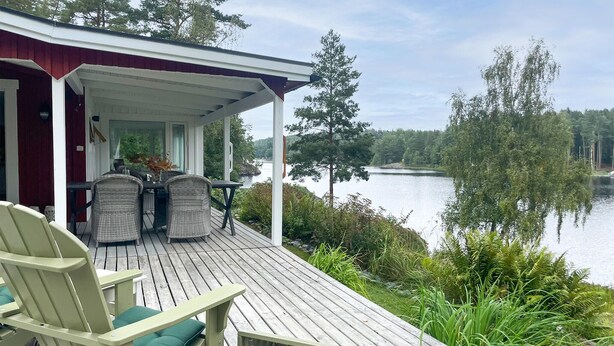 A wooden deck with outdoor furniture, a covered porch, and a lake view. - Beautiful home in Säffle with lake view (Säffle)