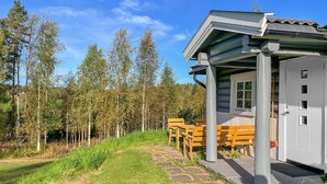 Una baita con un vialetto in pietra che conduce a un'area con panchine di legno, circondata da alberi.