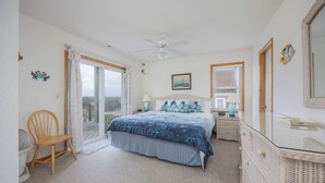 Une chambre à coucher comprenant un lit, une chaise, une commode, un ventilateur de plafond et une fenêtre.