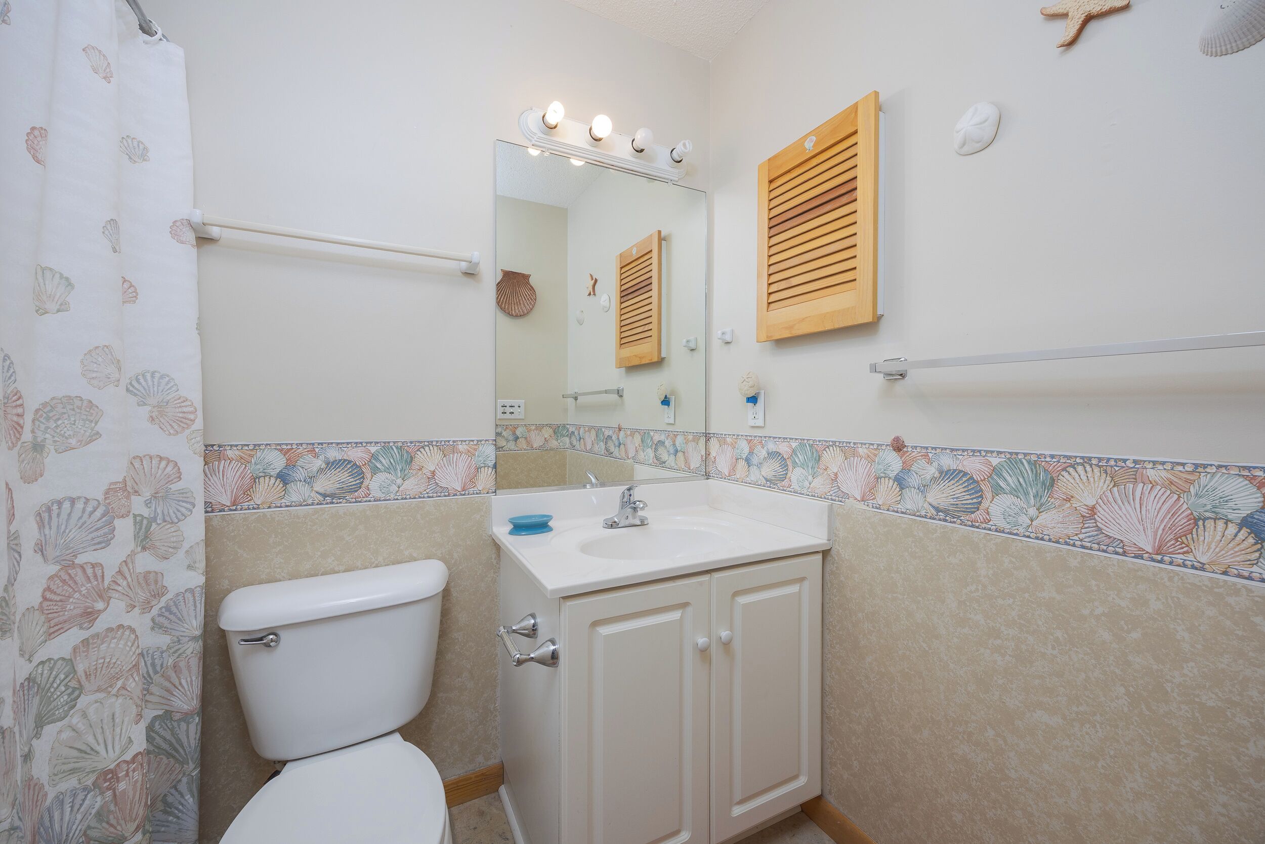 A bathroom with a toilet, sink, mirror, and shower curtain.