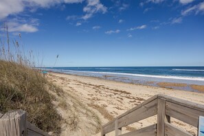 A beach with a wooden walkway leading to the shore, sandy beach, and ocean.