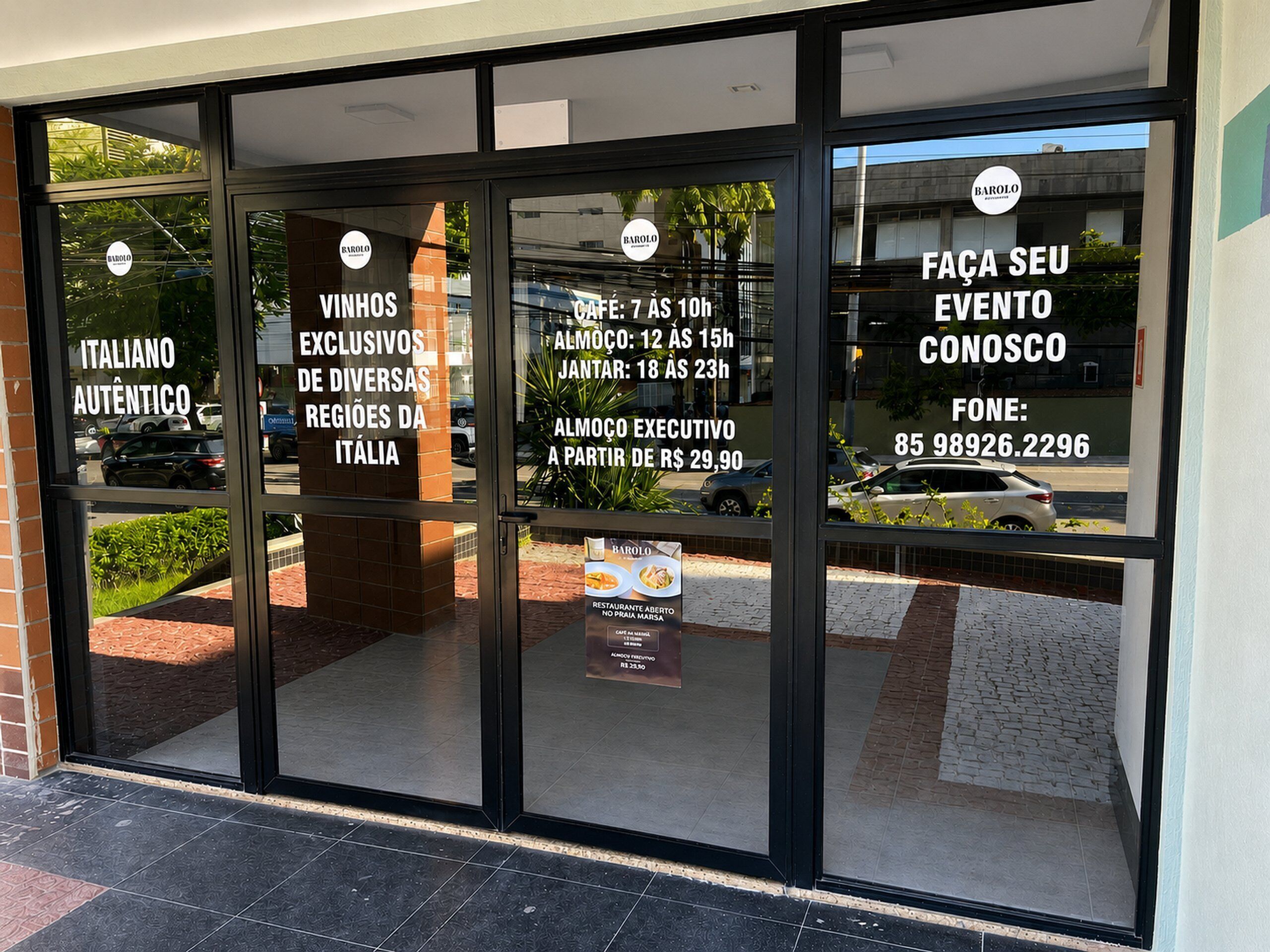 A restaurant with glass doors, a sign advertising Italian authentic cuisine, and a contact number.